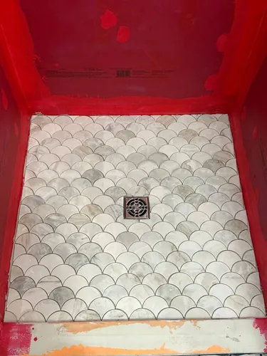Fan-scale marble mosaic set on the shower floor around the drain