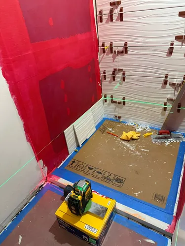 Textured white plank wall tile going up to a laser line with leveling clips