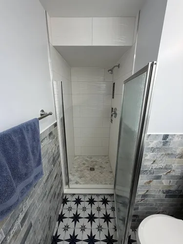 Finished shower with glass door, plank tile walls and marble mosaic floor