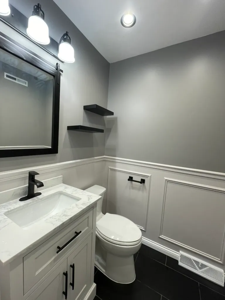 Finished powder room with new vanity, black floor tile, grey walls and bright lighting