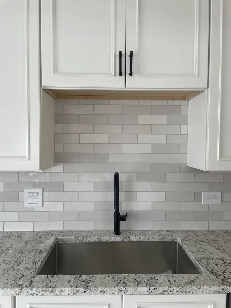White cabinets with black faucet and granite counter