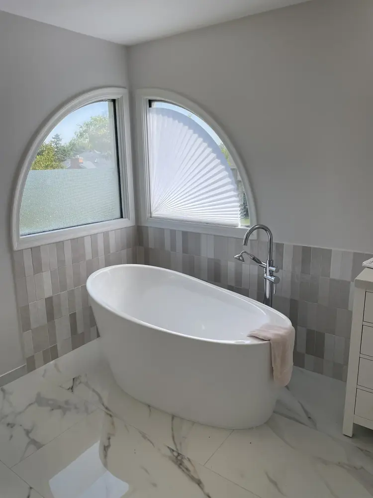 Finished bathroom with freestanding tub, large-format tile floor, and updated vanity